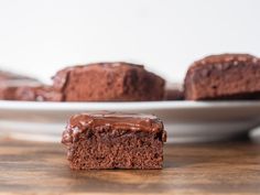 two pieces of chocolate brownie on a plate with one piece cut out and the other half eaten