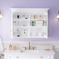 a bathroom with purple walls and gold faucets on the sink, along with white cabinets