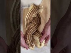 a person holding a piece of bread in their left hand and the other one with braids wrapped around it