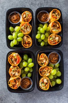 four black trays filled with different types of food and some grapes on the side