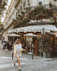 a woman crossing the street in front of a cafe