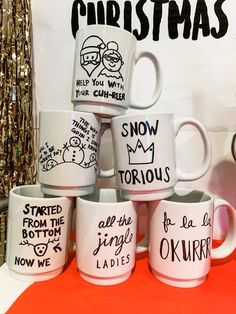 six coffee mugs are stacked on top of each other in front of a christmas sign