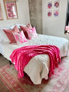 A college apartment room with a white bed and pink pillows and blankets with a pink rug. College Room, Preppy Room Decor