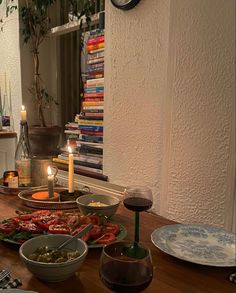 a table topped with lots of plates and bowls filled with food next to a clock