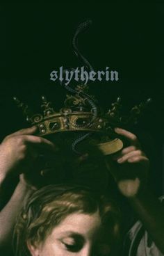 a man holding a crown over his head with the word slyferin on it