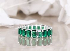 an emerald colored ring sits on a white surface