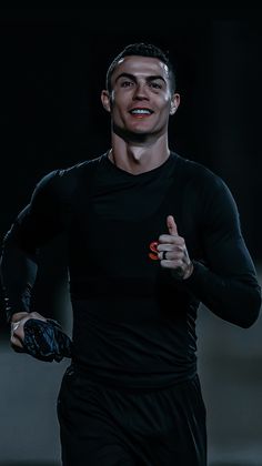 a man is running in the dark with his hand on his hip and wearing a black shirt