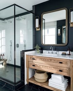 a bathroom with black walls and white tile flooring, two mirrors on the wall