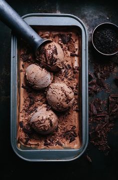 an ice cream dish with chocolate chunks in it and a scoop of cocoa powder next to it