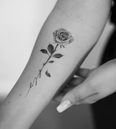 a woman's arm with a rose tattoo on it