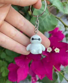 a hand holding a keychain with a white stuffed animal on it