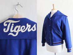 "Vintage Sweeney Sportswear varsity jacket in vibrant cobalt blue woven woolen type fabric with classic letterman jacket style boxy shape, sailor style collar, snaps down front, welt pockets at hips with blue leather-look trim, long sleeves, athletic-style blue, white, and purple stripe knit banded trim along cuffs and hem, off white satin appliqué 'Tigers' in script on back collar, full black quilted lining. Good vintage condition - some overall wear. full garment measurements: bust: 46\" waist Veiled Hats, Sailor Style, Sailor Fashion, Blue Tigers, Letterman Jacket, Silk Shorts, Vintage Coat, Athletic Fashion, White Satin