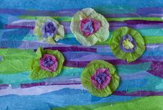 some paper flowers and leaves are on the tablecloth with blue, green and purple strips