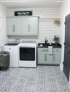 a laundry room with white cabinets and black counter tops, gray tile flooring and a washer and dryer in the corner