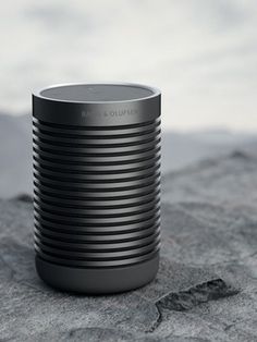 a black and silver speaker sitting on top of a rock