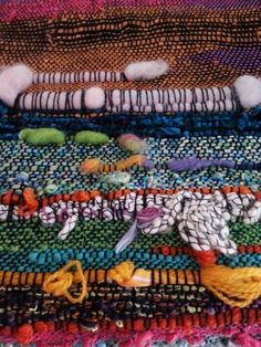 a pile of multicolored rugs with different patterns and colors on top of each other