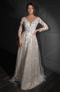 a woman in a long sleeved wedding dress with sequins on the sleeves