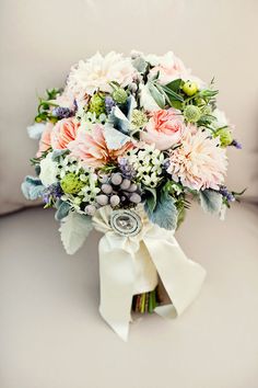 a bridal bouquet with pink and white flowers on a couch in front of a window