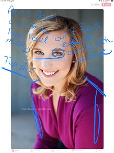 a woman with blue writing on her face and handwritten words above her head, smiling at the camera