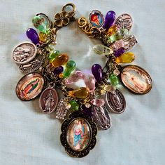 Our Lady of Guadalupe Cameo charm bracelet. The bracelet consists of mixed metals, gold tone and brass. Different Guadalupe medals in Silver, Three of the charms are Guadalupe images I've made from vintage prayer cards. Sized down and set into brass bezels.  Silver double sided Italian medals Our Lady of Guadalupe/Our Juan Diego. I've used this one twice with each on image on the front one time.  Also, Virgin del Cobre/Pray for Us. San Juan of Los Lagos/Pray for Us There are 4 silver single side Spiritual Multicolor Charms Jewelry, Multicolor Our Lady Of Guadalupe Jewelry As A Gift, Multicolor Our Lady Of Guadalupe Jewelry Gift, Spiritual Souvenir Bracelet Jewelry, Spiritual Bracelet Souvenir Jewelry, Spiritual Our Lady Of Guadalupe Bracelets As Gifts, Gold Spiritual Bracelet With Vintage Charm, Multicolor Vintage Charm Jewelry As A Gift, Cross Medal