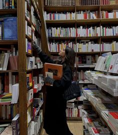 a woman is reaching up to reach the bookshelf in a library with many shelves full of books