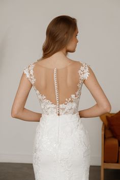 a woman in a white wedding dress with an open back and beading on it