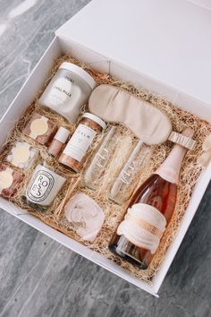 an open box containing bottles of wine and other condiments on a marble surface