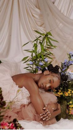 a naked woman laying on top of a bed next to flowers