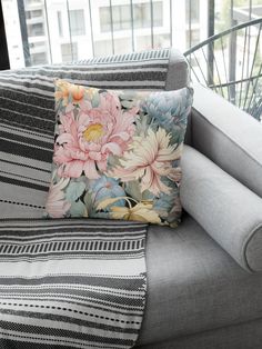 a flowered pillow sitting on top of a gray couch