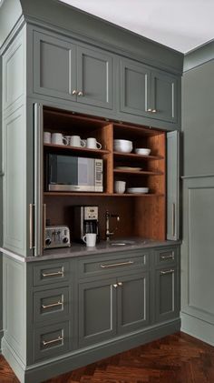 a kitchen with gray cabinets and wooden floors