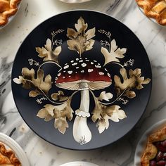 a black plate topped with a mushroom surrounded by other plates filled with pies and fruit