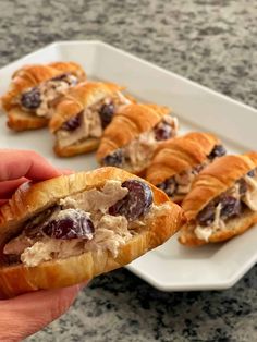 a hand holding a croissant filled with meat and cheese