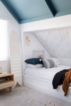 a white bed sitting under a blue skylight in a bedroom next to a window