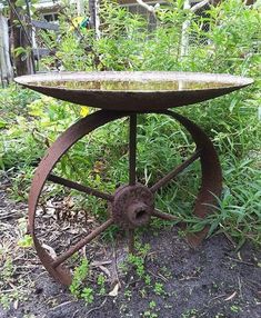 an old rusty table sitting in the middle of some grass and dirt with weeds growing around it