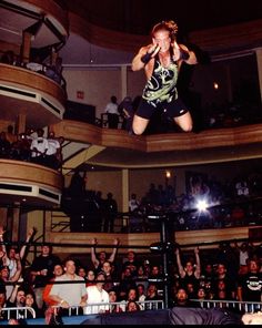 a woman jumping in the air on top of a wrestling ring