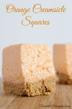 two pieces of orange creamsice squares sitting on top of a wooden cutting board