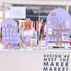 a woman standing in front of a table with items on it and a sign that says design 4 meet the maker market