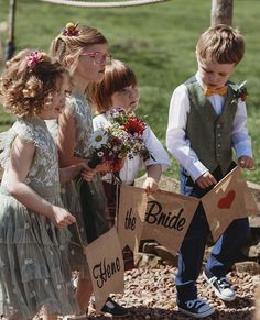 three children holding up signs that say the bride and two boys are standing next to each other