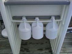 three white jugs sitting on top of a wooden floor