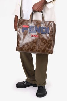 Fendi x Fila Brown Coated Canvas Zucca Mania Tote with Strap. Dual handles. Open top. Blue felt textile interior lining. Single interior wall flap with zip pocket. Detachable strap. Gold-tone hardware. Dimensions: 15" width x 13.5" height x 7.25" depth x 5.5" handle drop x 18" strap dropCondition: This item is in good pre-loved condition. Mark to the front and bottom. Wear on the outer corners. Fraying on the base of the handles. Designer Brown Bags With Lined Interior, Cottagecore Bag, Mens Spring Shoes, Pop Clothing, Wrist Stacks, Summer Clearance, Chanel Jewelry, Brown Coat, Iconic Bags