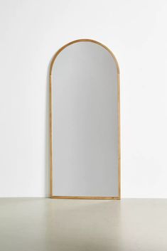 an arched wooden mirror against a white wall