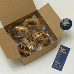 a box filled with chocolate chip cookies sitting on top of a white table next to a blue sticker