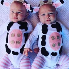 two babies laying next to each other on top of a white blanket covered in pink and black polka dots