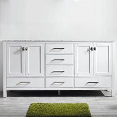 a white bathroom vanity with two sinks and green rug on the floor in front of it