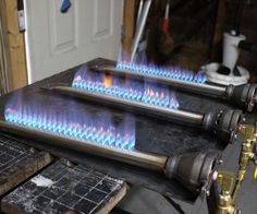 three burners with blue flames on them in a garage