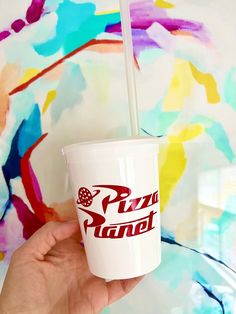 a person holding up a cup with a straw in it that says pizza planet on the side