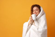 a woman wrapped in a blanket holding a coffee cup