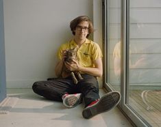 a man sitting on the floor holding a cat