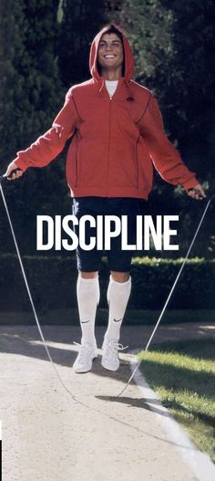 a man in a red jacket and white socks is holding a string with the words discipline on it