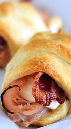 two pastries on a white plate with meat and cheese in the pastry wrapper